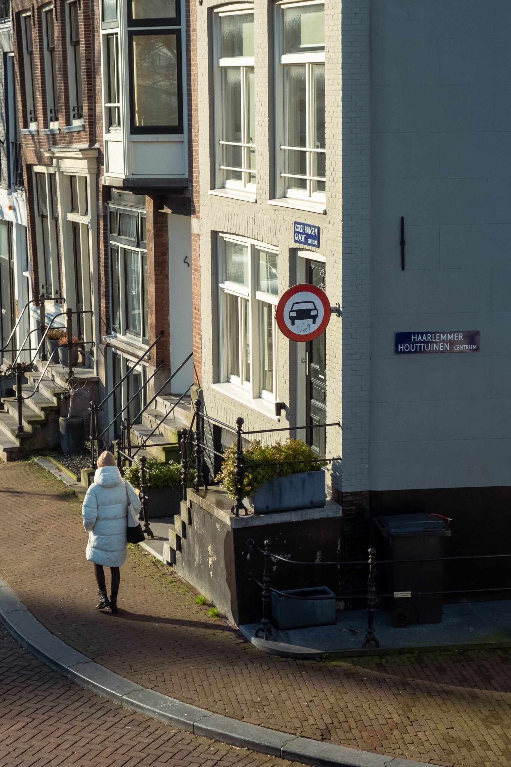 Back view of a woman walking on a sidewalk in a charming urban setting with traditional architecture.