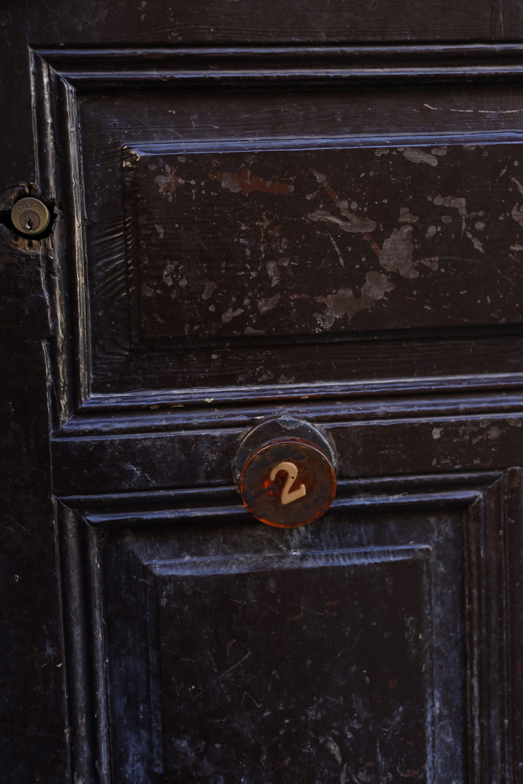 Verkoop Close-up of an old wooden door featuring a number two sign, showcasing vintage texture.
