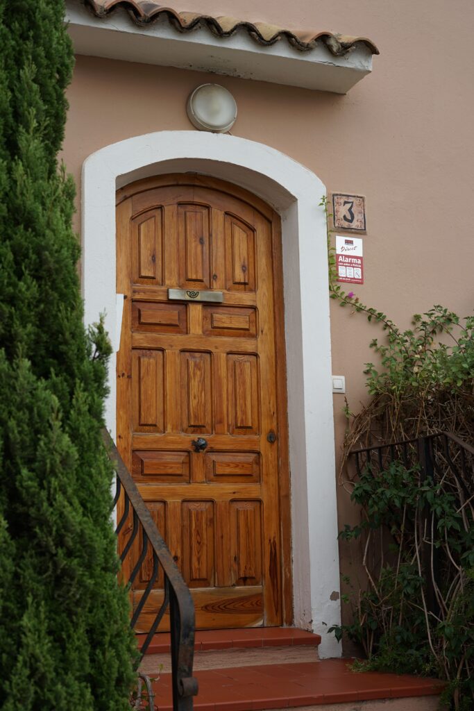 Verkoop A rustic wooden door framed by greenery and subtle architectural details.